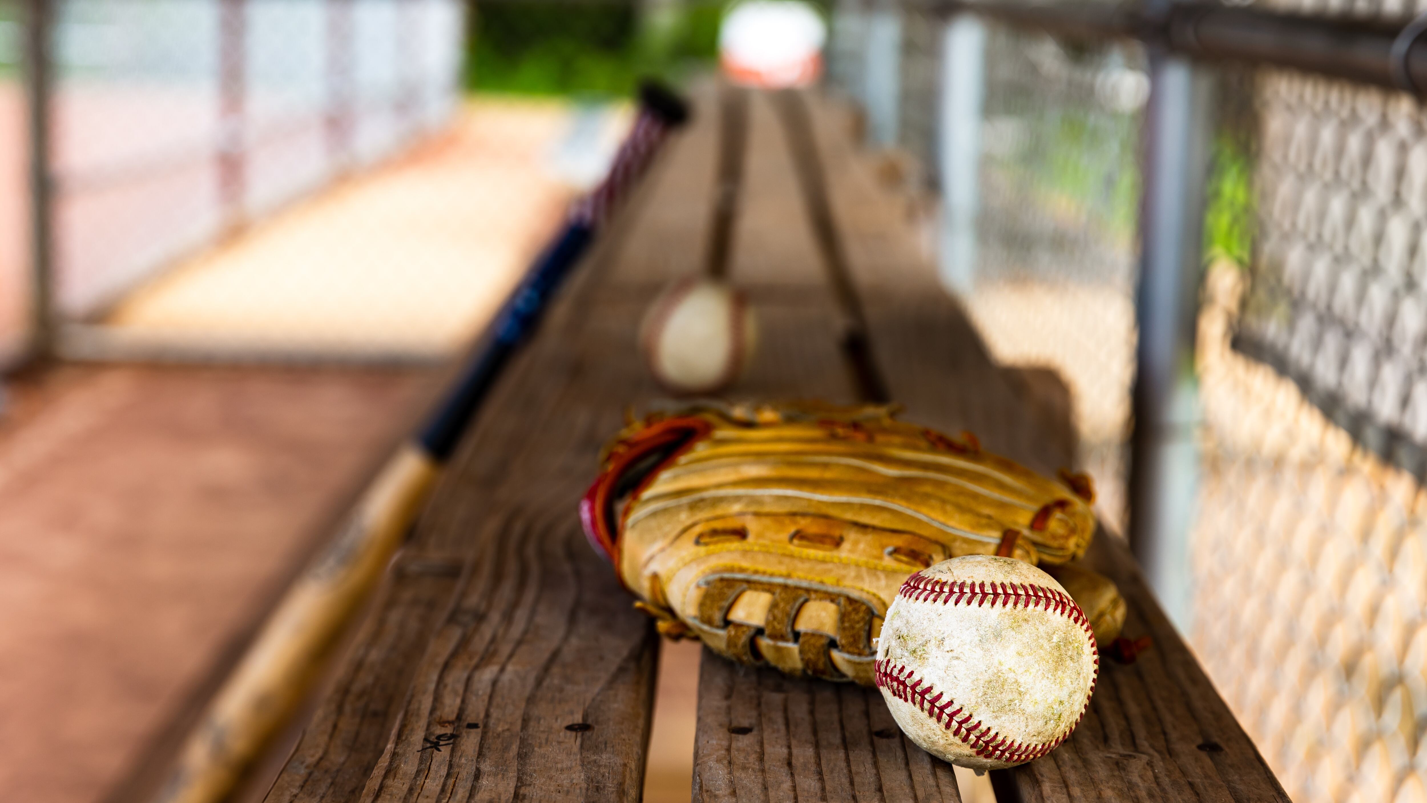 Baseball and glove on dugout bench with blurred background