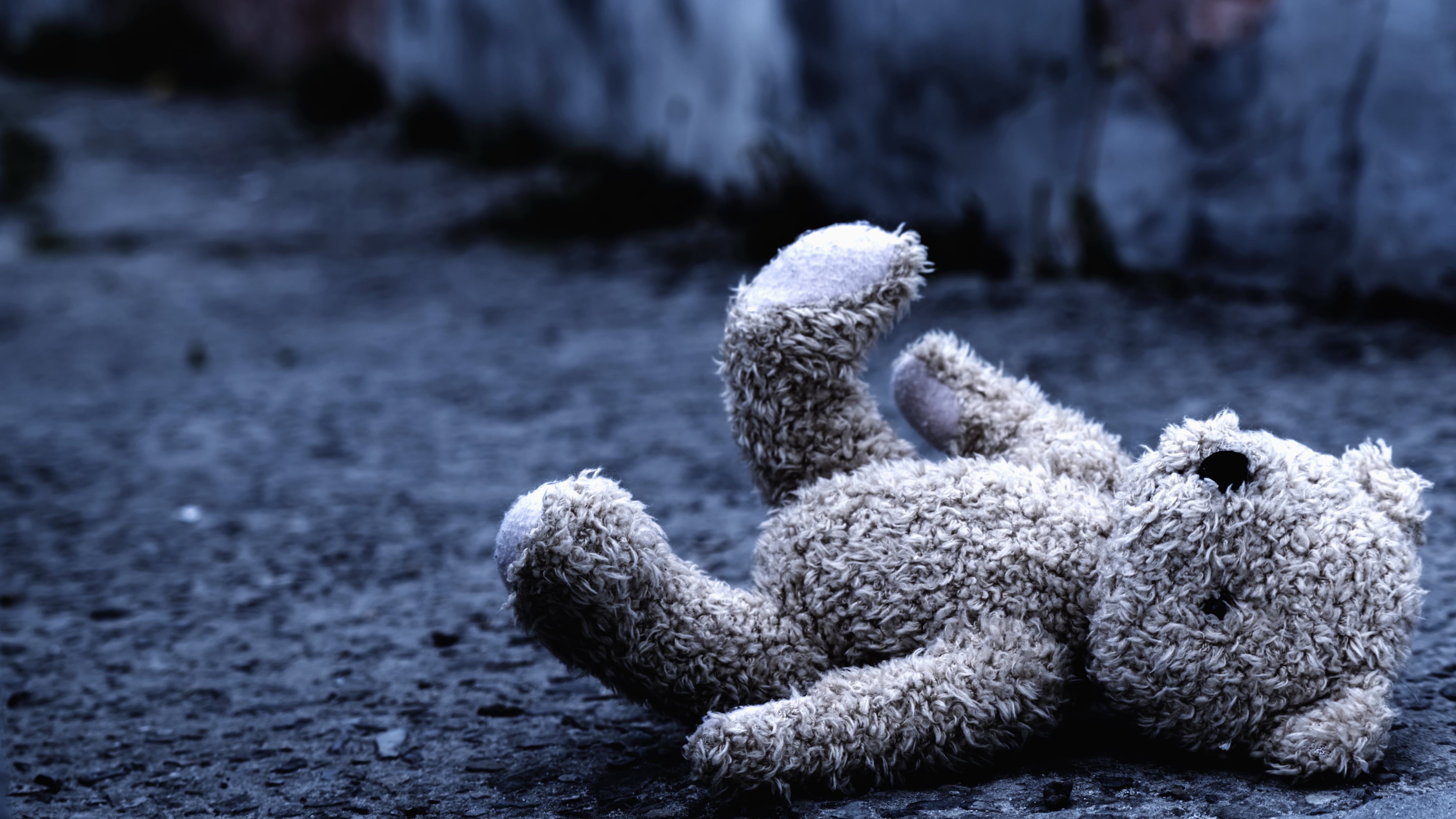 Teddy bear toy forgotten on the street as symbol of children's loneliness, pain, broken childhood and loss future.