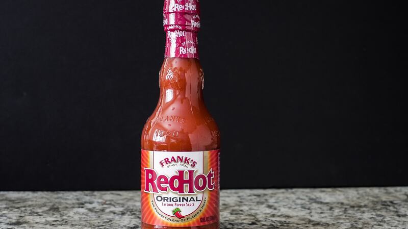 Frank's redhot original hot sauce bottle standing on a granite kitchen counter